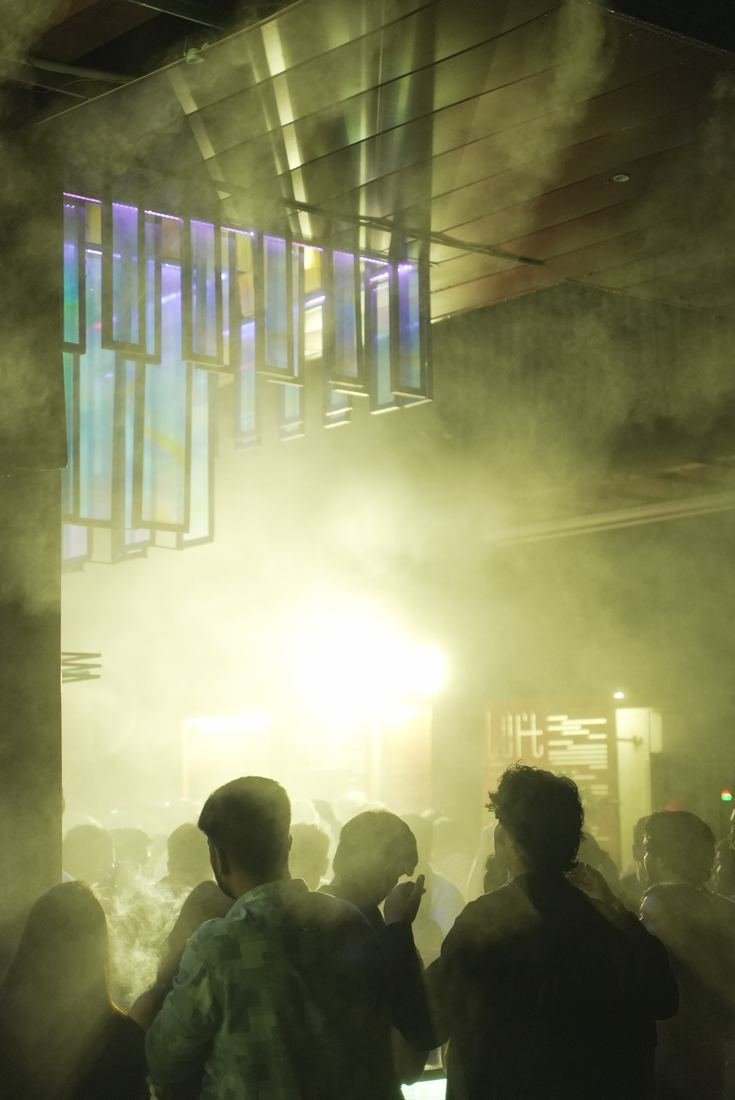 Crowd at a concert under stage lights and haze