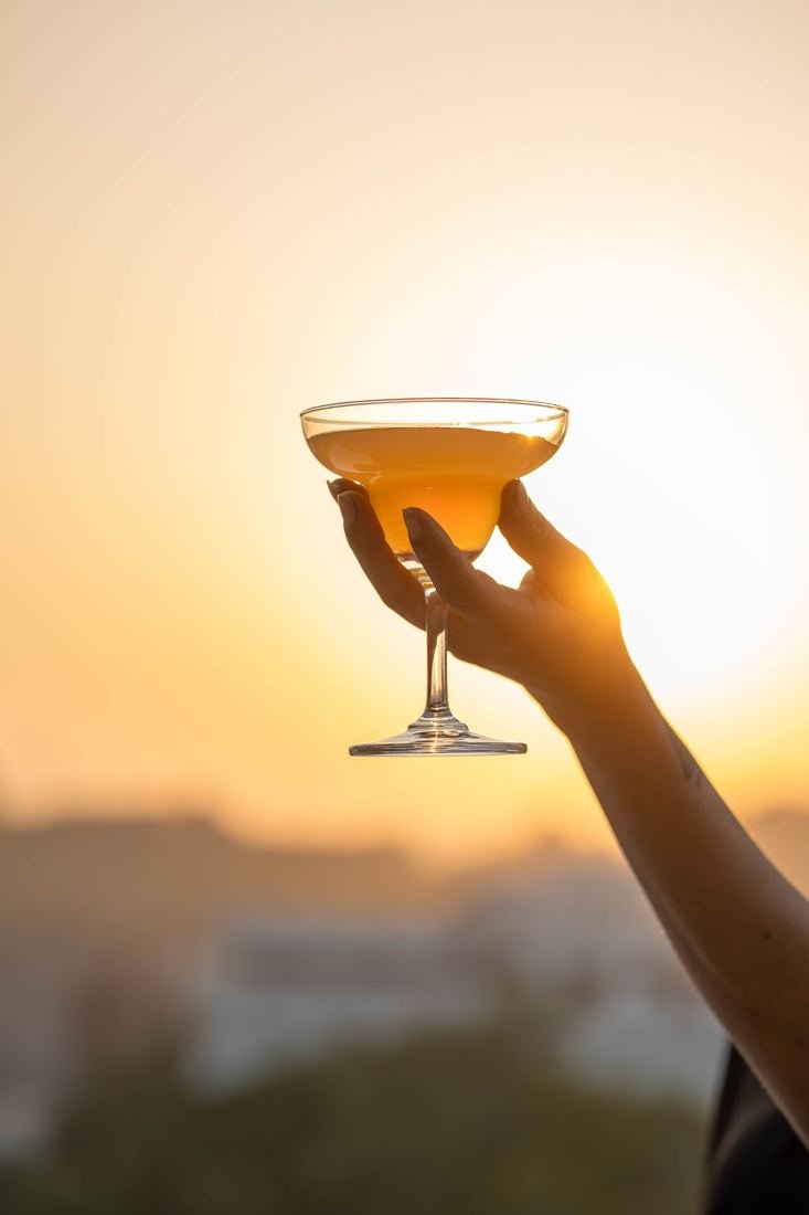 Cocktail glass raised against a sunset