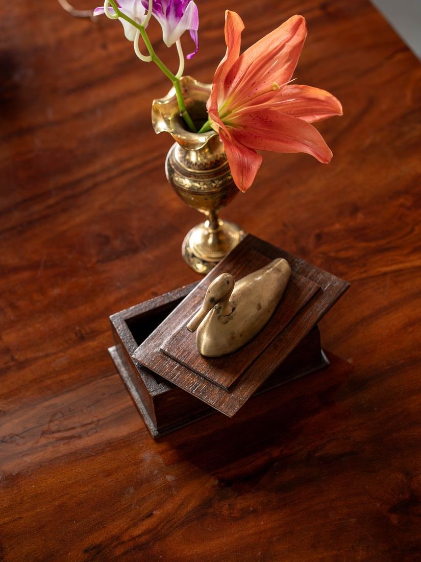 Brass vase with a lily on a wooden box